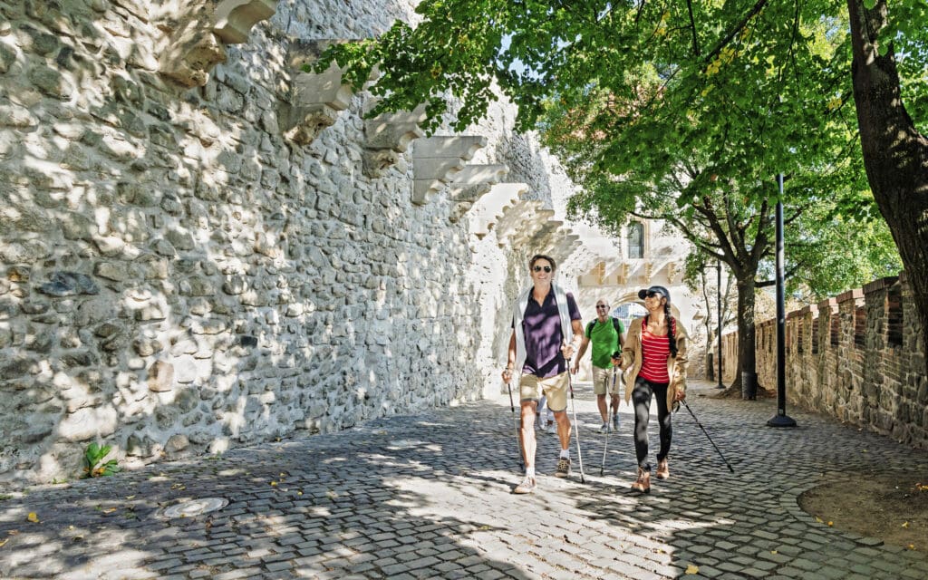 3 people w hiking sticks walk the cobbled streets of Bratislava Castle