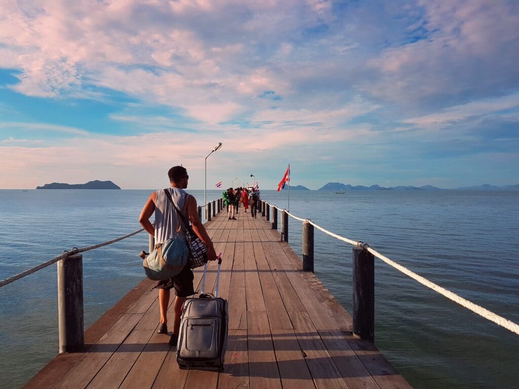 Man on long pier to Koh Tao carrying luggage