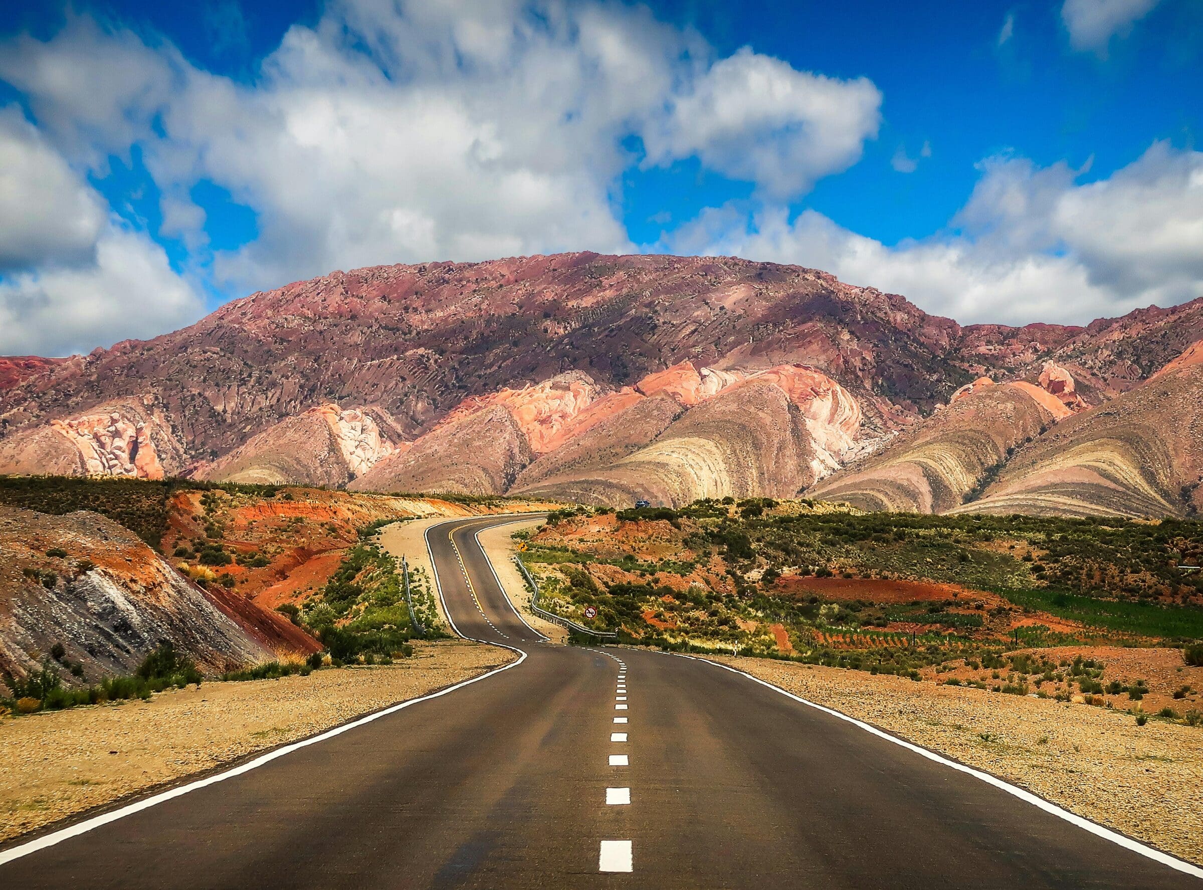 Concrete Road Near Brown Mountain Under Blue Sky