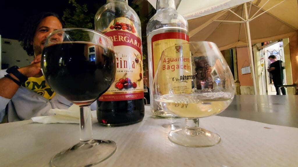 a glass of deep red Ginja and a snifter of clear Aguardente. 