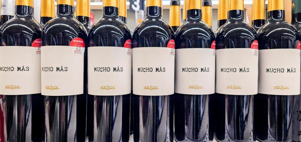 a row of wine bottles with a lite label that say Mucho Mas