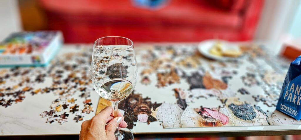 Glass of white wine in front of a puzzle of pups