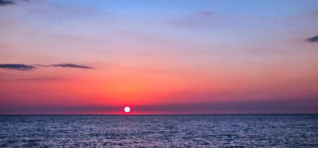 hot pink sun sets over the ocean