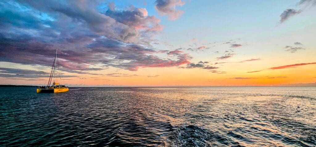 Yellow catamaran out on the ocean at sunset