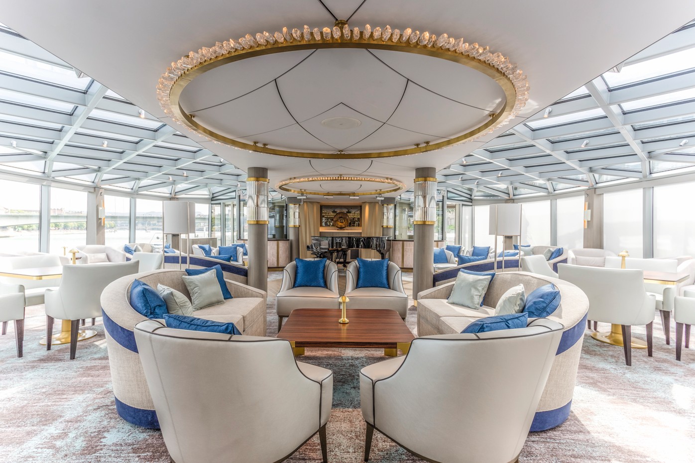 off-white lounge chair w blue cushion inthe Palm court of Riverside river cruise ship