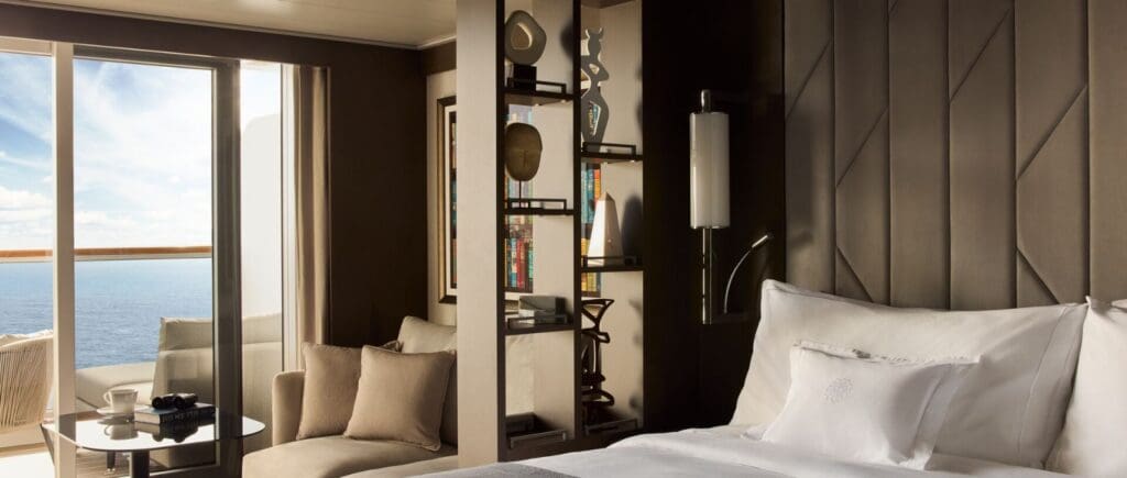 Luxury Cruise cabin on the Explora I; Fluffy white pillow on bed, sea terrace in background.